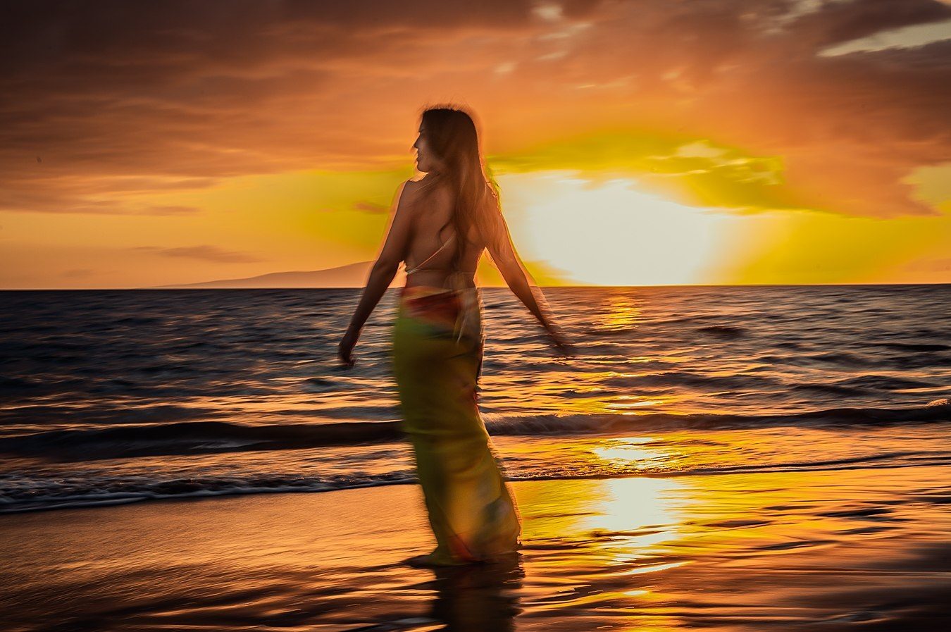 Color long exposure of a figure in silhouette against a glowing orange sunset over the sea