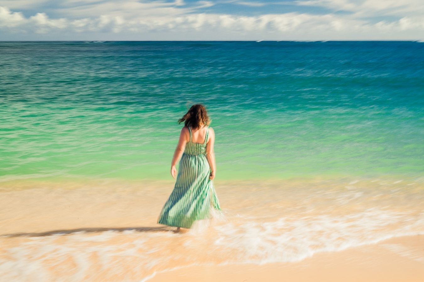 Color long exposure of a woman in a green striped dress walking toward the sea
